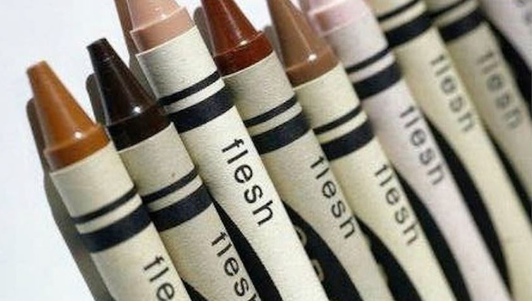 Picture of several crayons in various shades of human skin tone, with each crayon labeled "flesh"