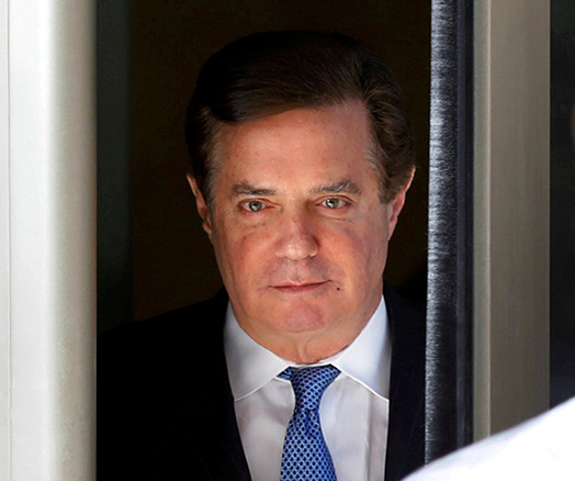 Picture of Paul Manafort standing in a doorway, wearing a white shirt, blue tie, and black suit jacket