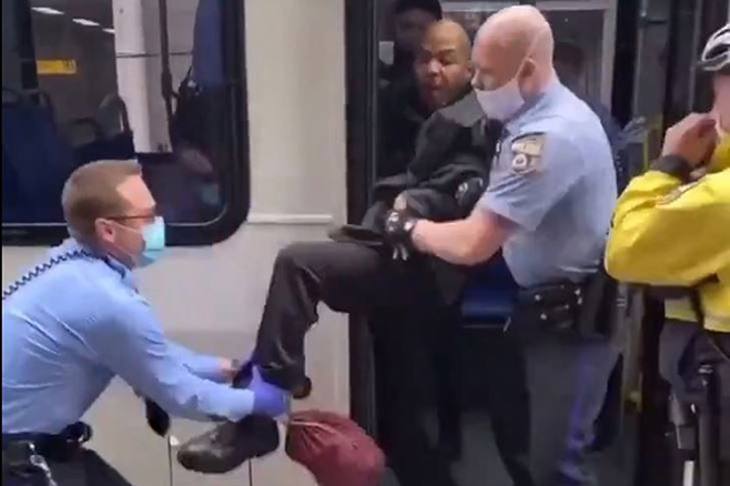 A still image from a video of a SEPTA passenger being ripped off the bus by several police officers